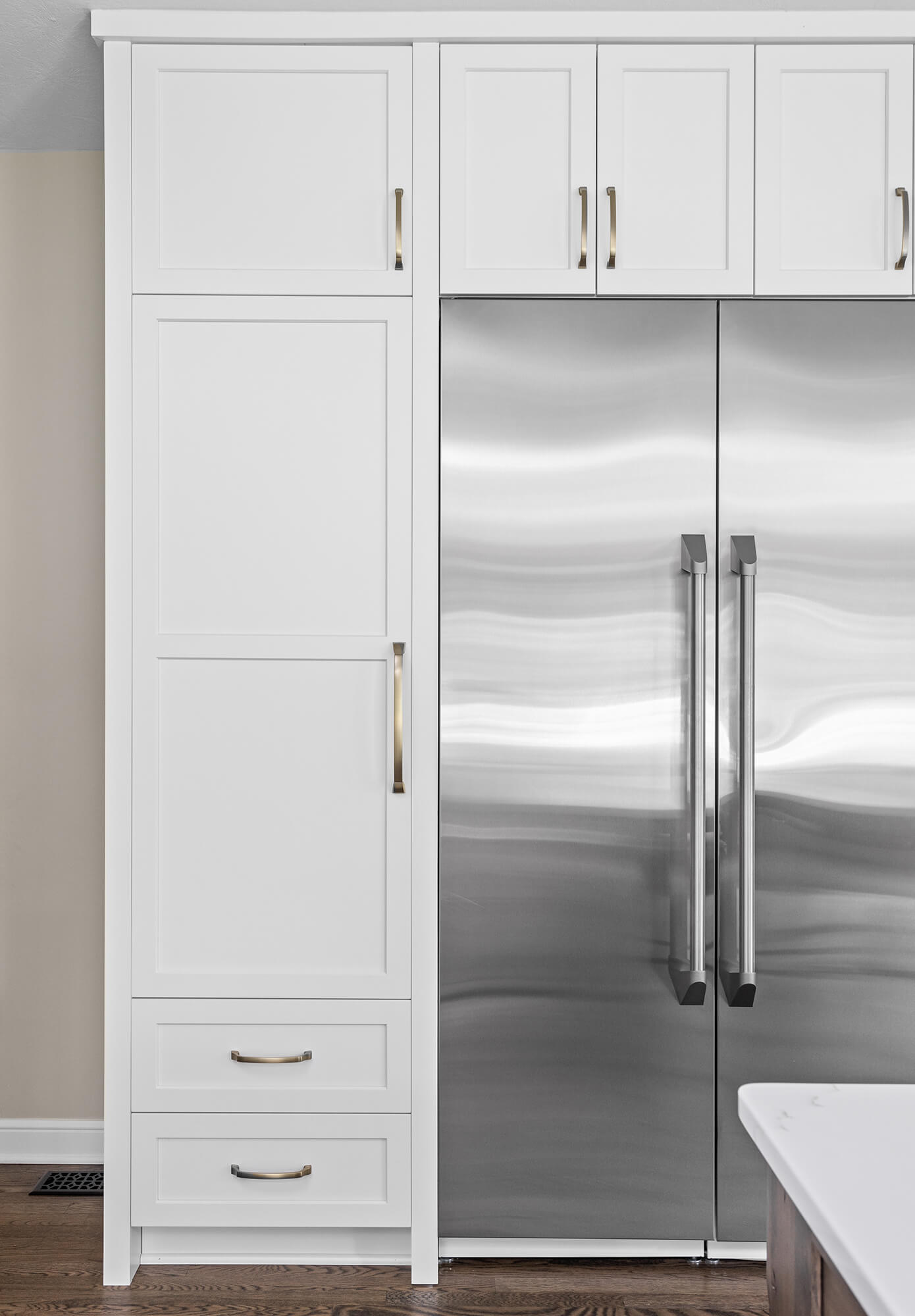 White shaker cabinetry around a stainless steel fridge.