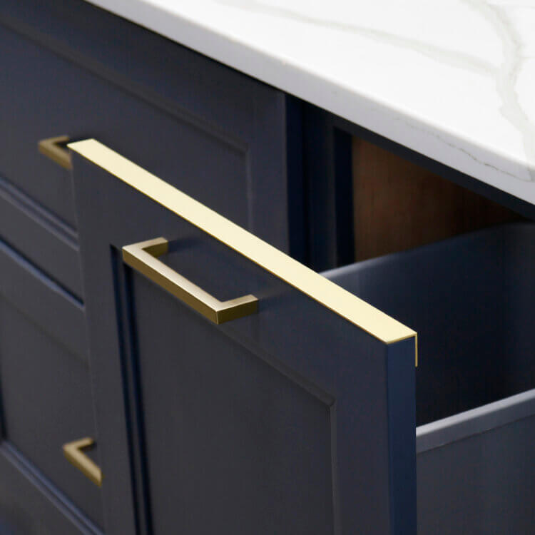 A brass metal drip edge to protect the trash/recycle bin cabinet door from drips and spills.