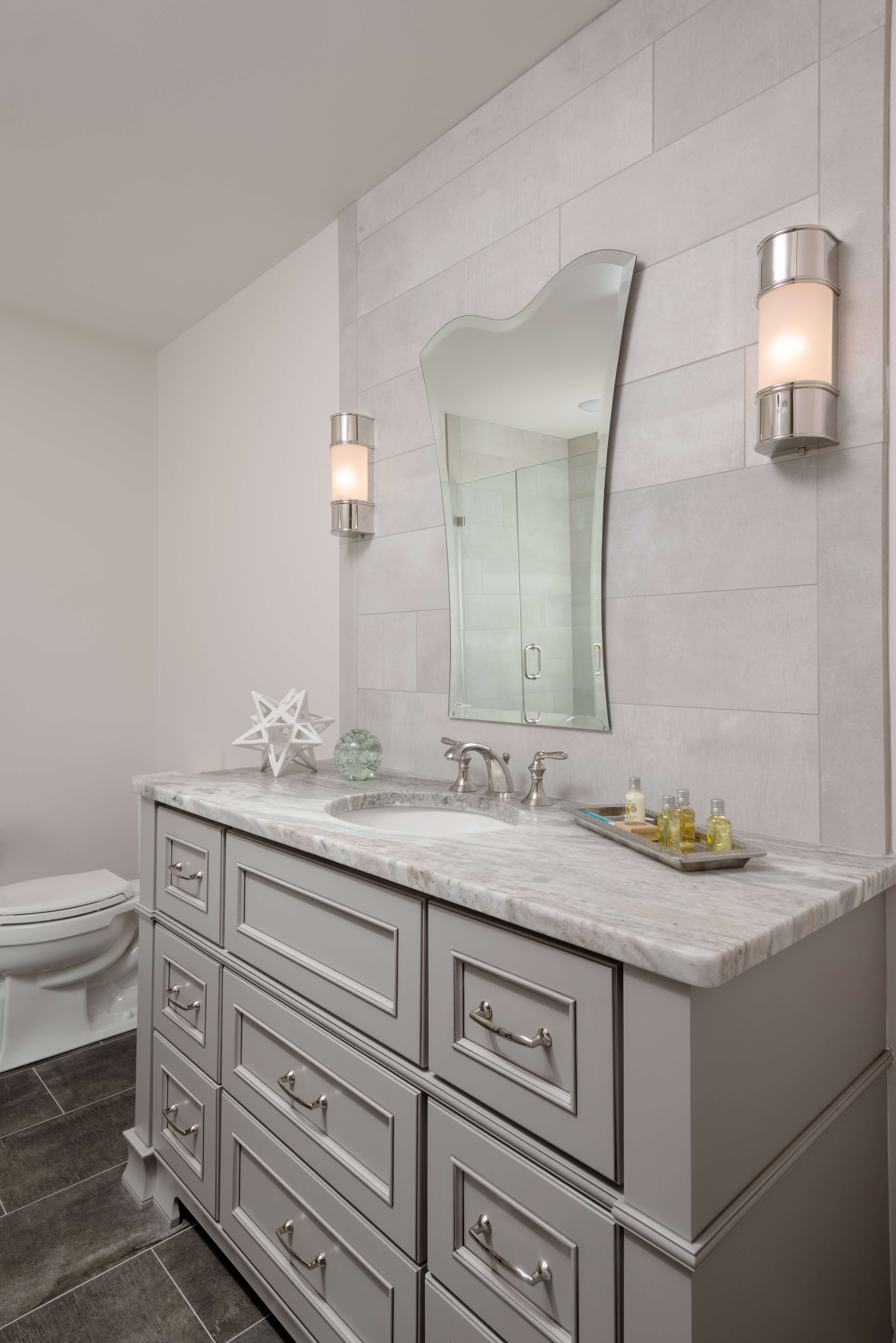 A light gray painted vanity with beautiful furniture style details and decorative molding.