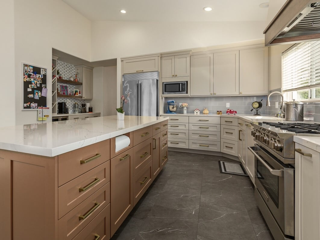 A transitional kitchen with natural, off-white painted cabinets with a light stained wood kitchen island.