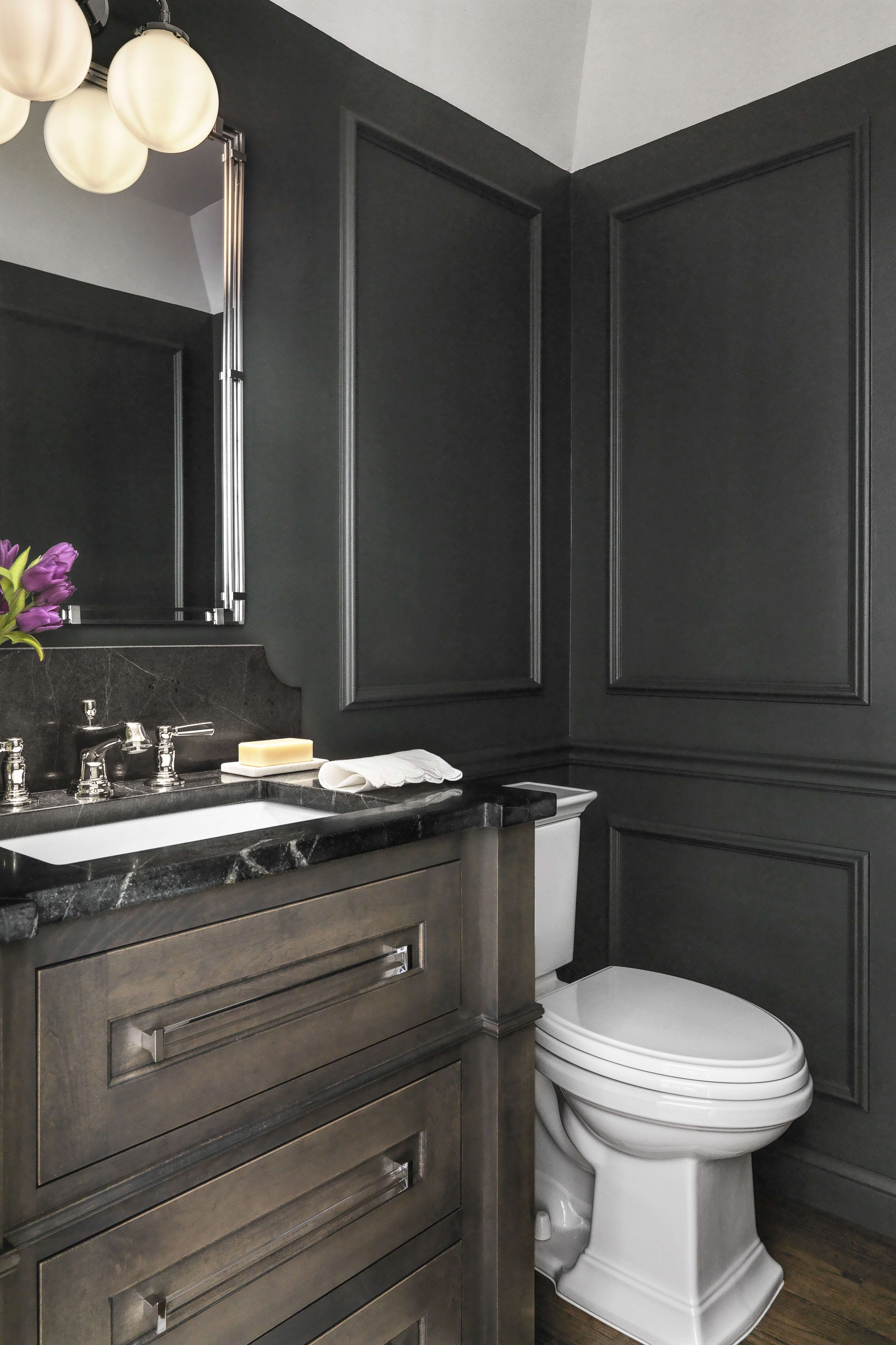 A dark and mood power room design with dark stained wood cabinets featuring a furniture style.