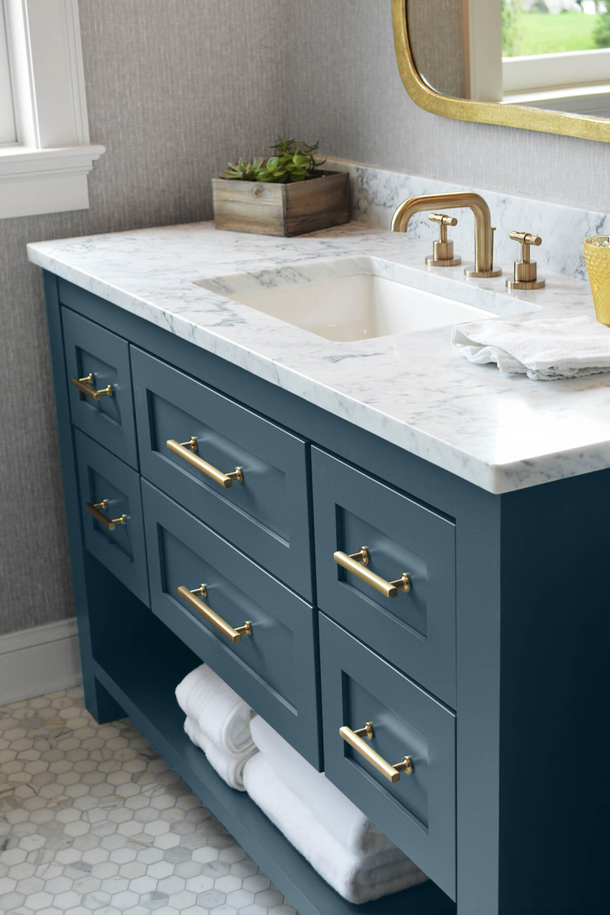 A dark ocean blue colored furniture style vanity with custom styled features.